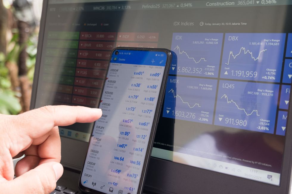 Image of a phone and a computer both displaying currency exchange rates and graphs.
