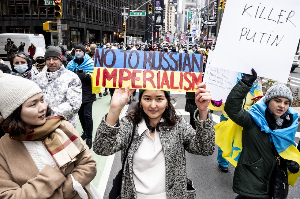 image of a protest with a woman holding a sign saying "no to Russian imperialism"