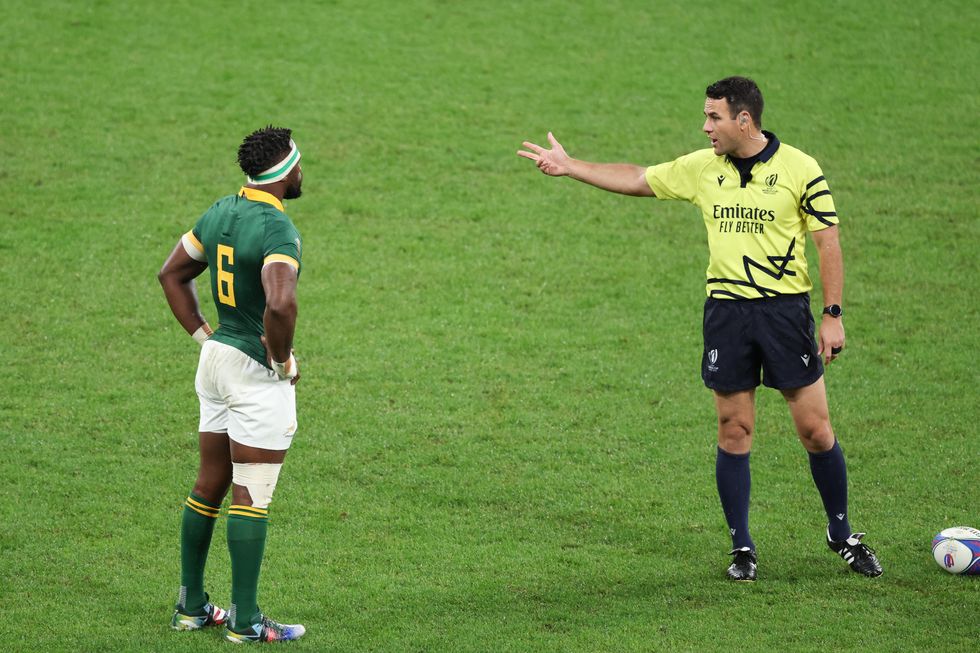 image of a referee talking to a rugby player on the field.