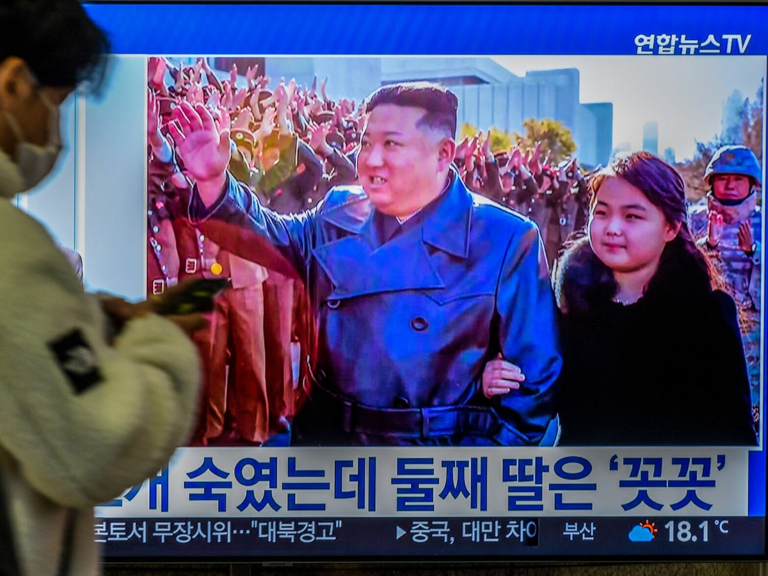 Image of a TV screen with North Korean leader Kim Jong-Un's second public appearance with his daughter during a photo session with officials when intercontinental ballistic missile