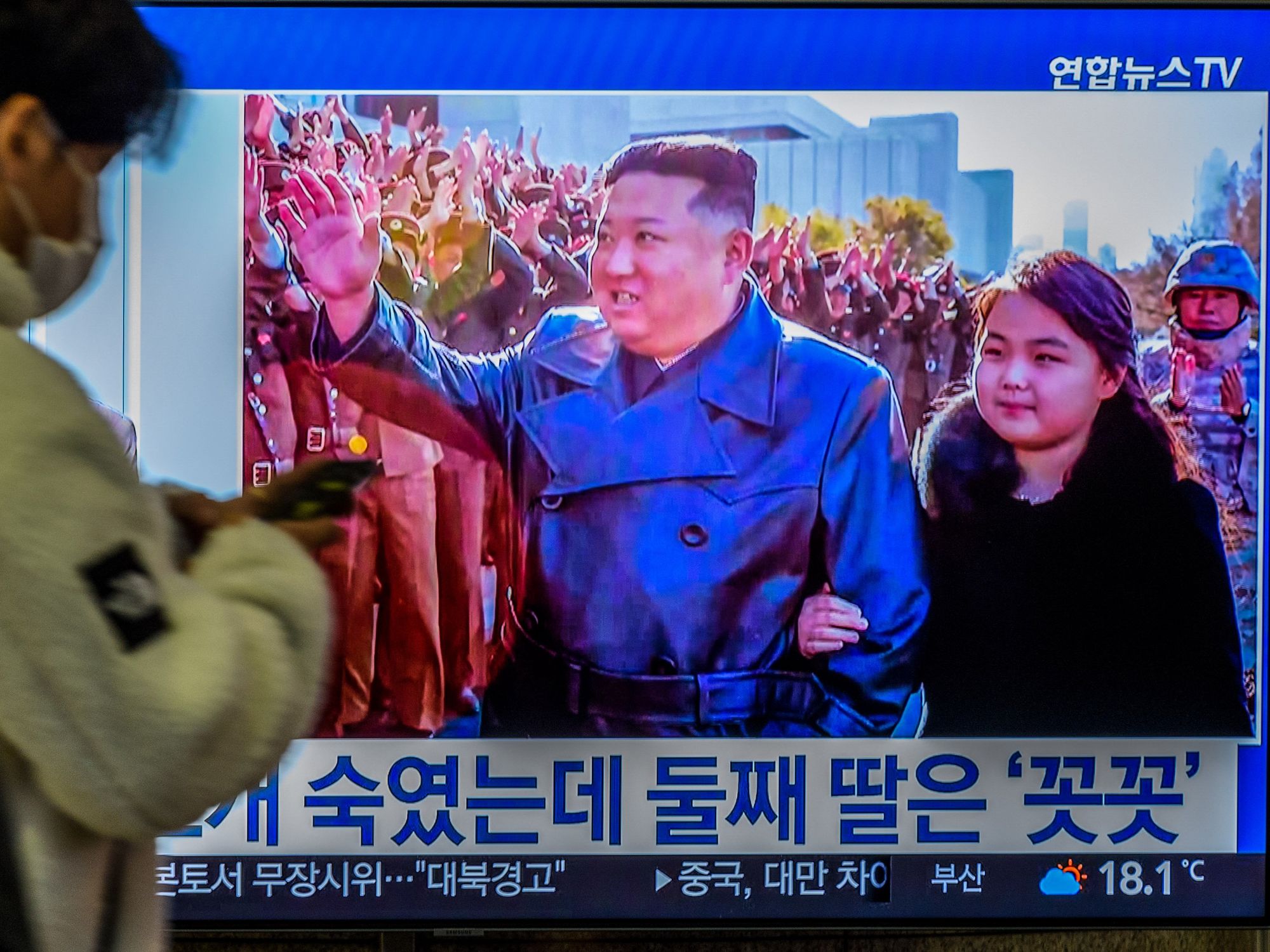 Image of a TV screen with North Korean leader Kim Jong-Un's second public appearance with his daughter during a photo session with officials when intercontinental ballistic missile