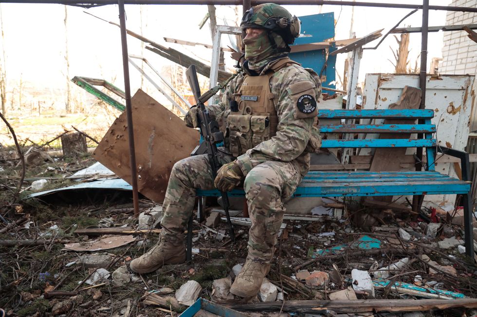 Image of a Wagner Group soldier sitting by a damaged building in the city of Artyomovsk (Bakhmut).