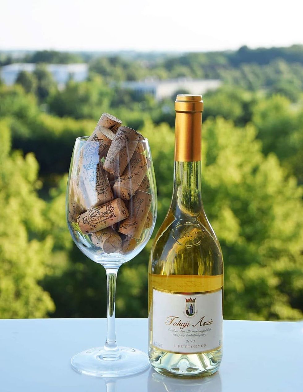 Image of a wine glass filled with corks and a bottle of white wine.