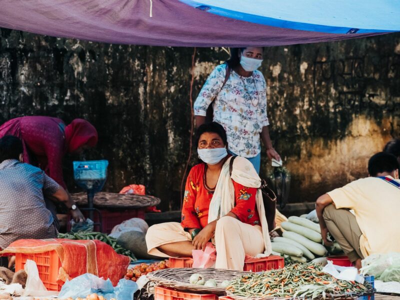 Image of A woman selling vegetables at the market and wearing a face mask during the COVID-19 pandemic.