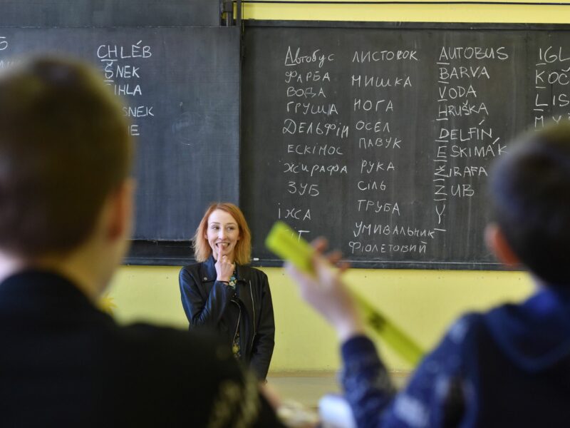 Image of a woman teaching a language to children in a classroom.
