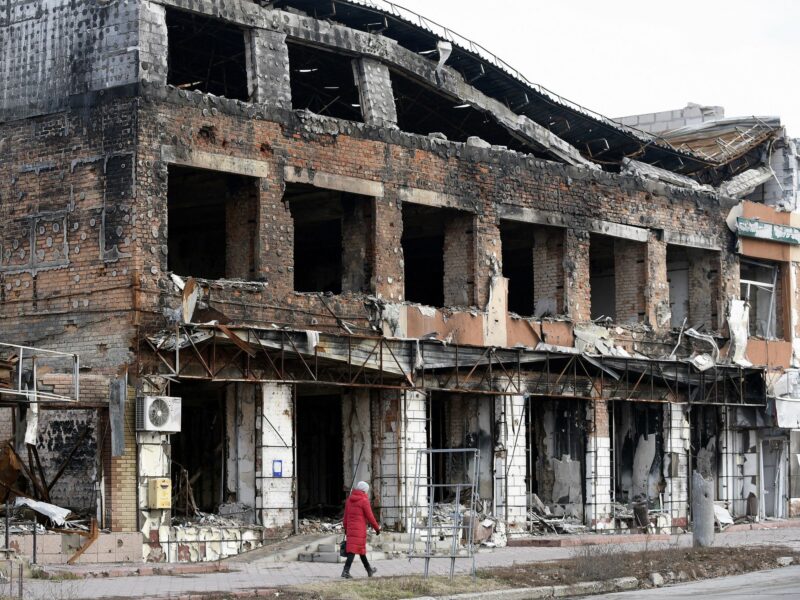 Image of a woman walking past a building destroyed in Russian shelling as seen in Izium liberated from Russian occupiers in the Kharkiv Region of Ukraine.
