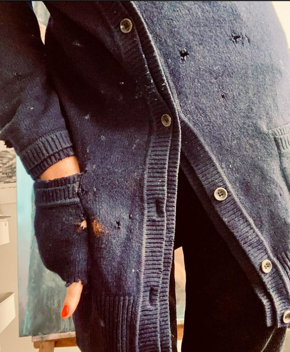 Image of a woman wearing a black cardigan with holes in it.