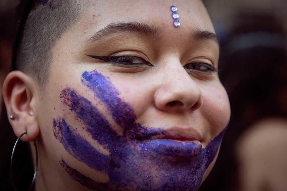 Image of a woman with a purple hand painted on her face, during a rally for International Women's Day in Buenos Aires, Argentina.