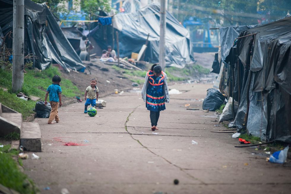 Image of an indigenous woman walking in a makeshift camp in Bogota, Colombia on May 9, 2022.