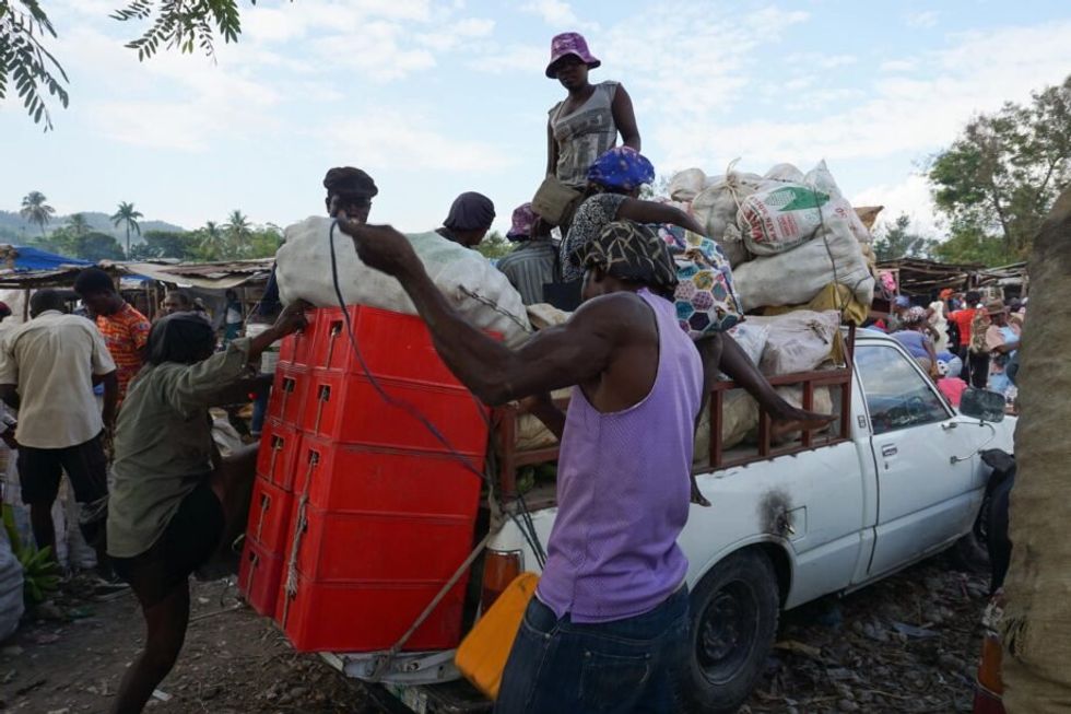 Image of bags of produce piling on top of a car and being transported.