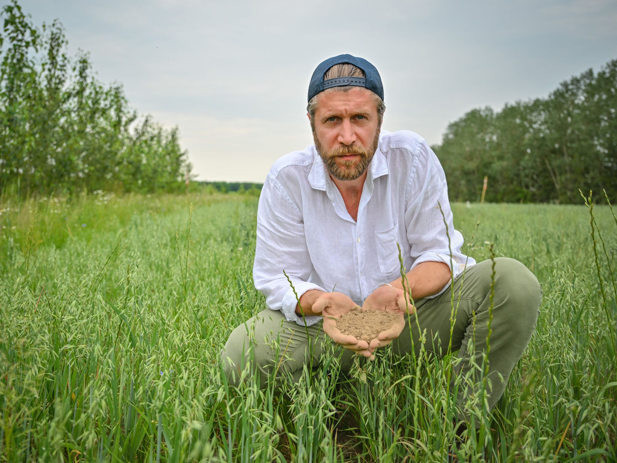 Image of Benedikt Büesel on an agroforestry plot with an oat field.