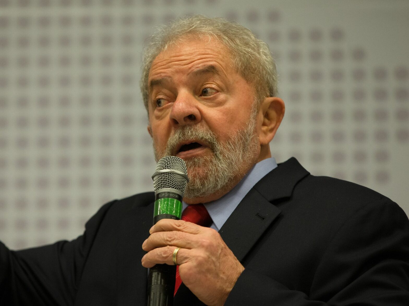 Image of Brazilian President Lula holding a microphone and speaking at a seminar.