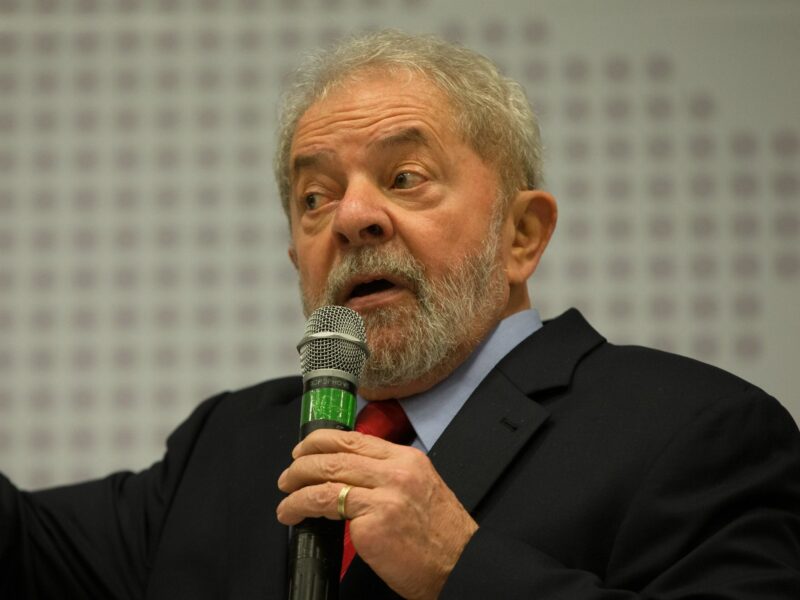 Image of Brazilian President Lula holding a microphone and speaking at a seminar.