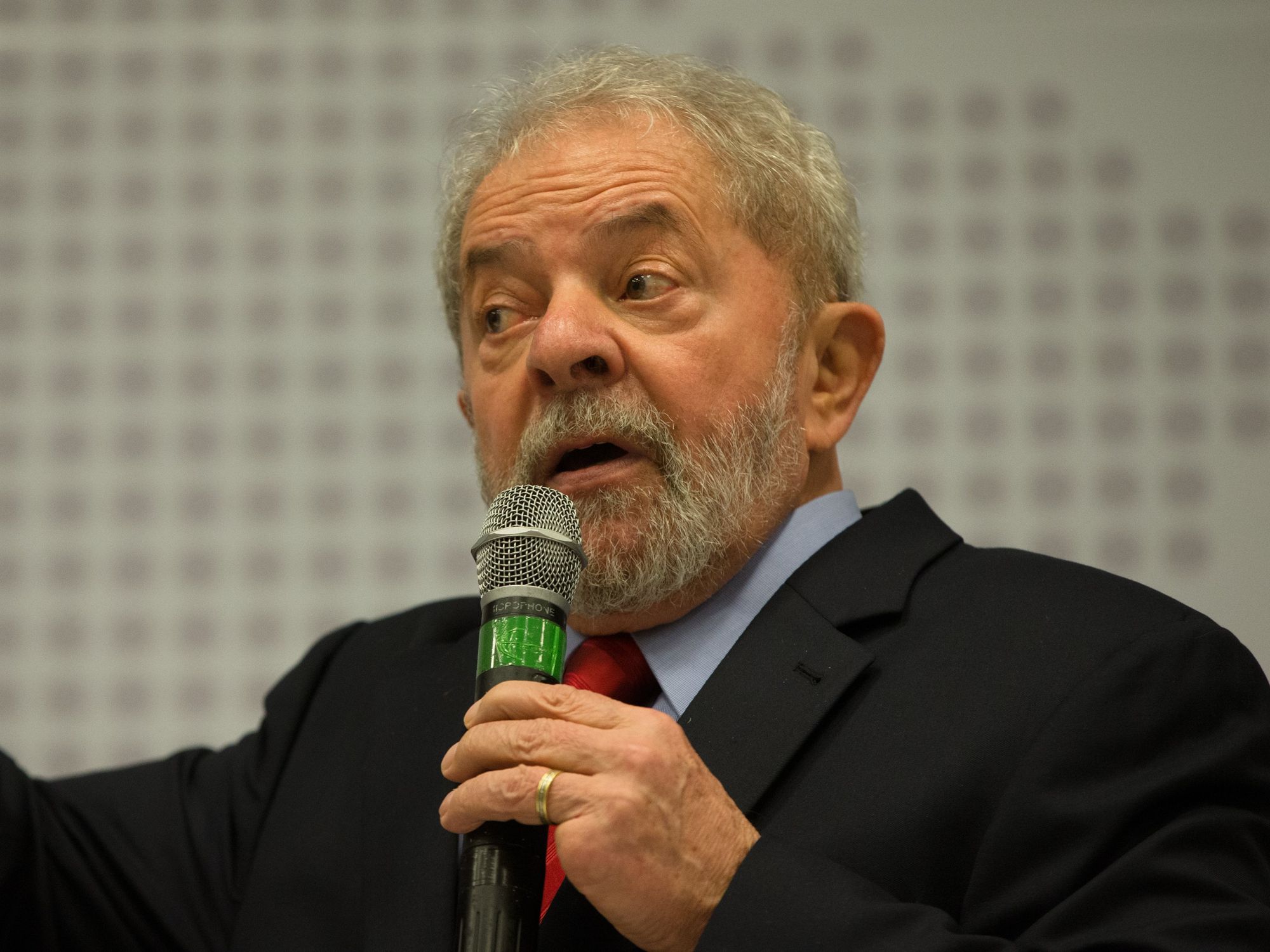 Image of Brazilian President Lula holding a microphone and speaking at a seminar.