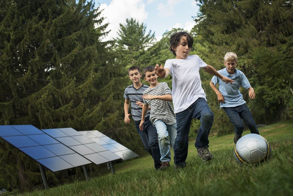 image of children playing with solar panels in the background.