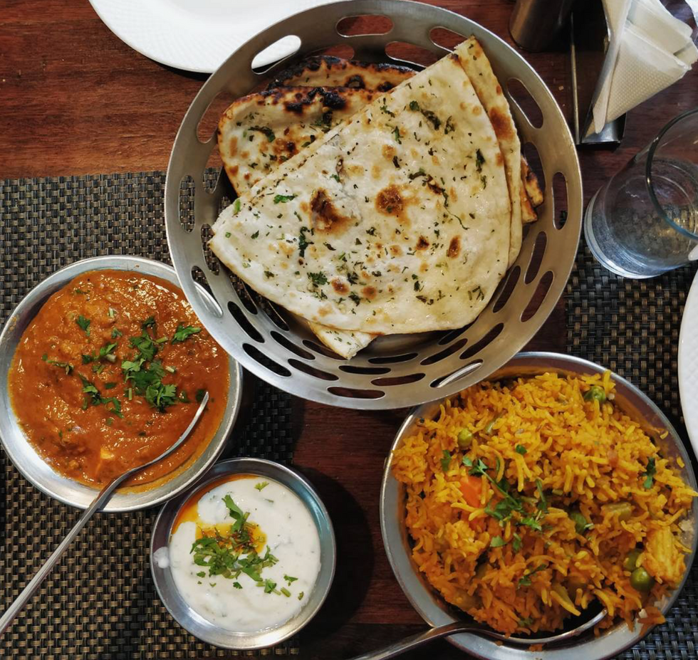 Image of curry, naan, biryani and homemade white sauce at the restaurant.
