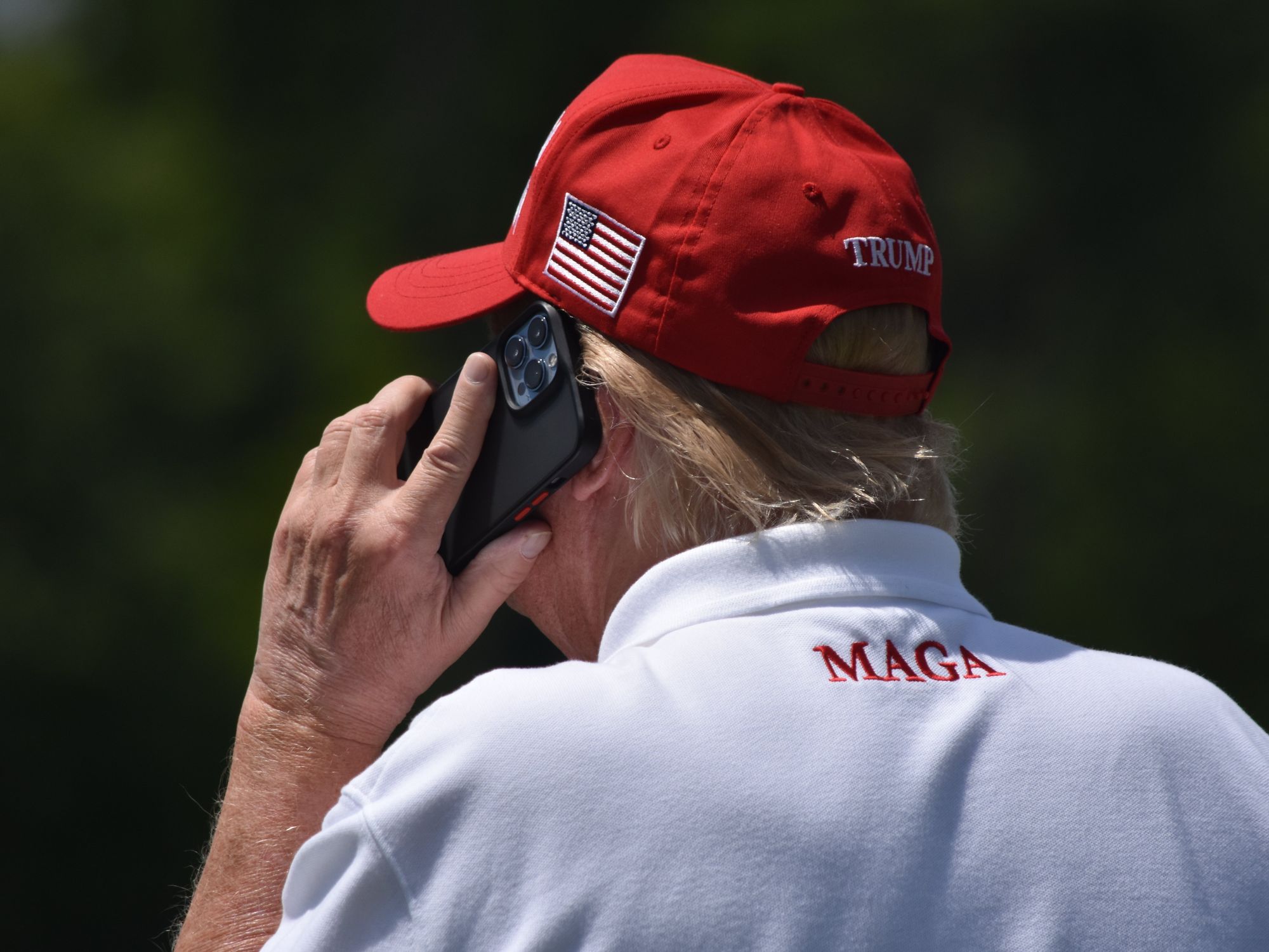 Image of Donald J. Trump taking a phone call as he visits the driving range