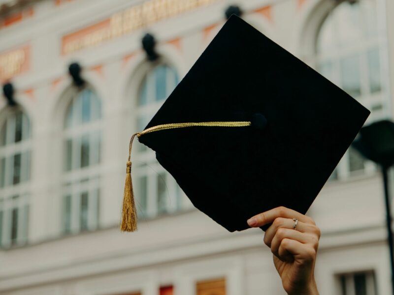 image of ​a person holding a graduate cap
