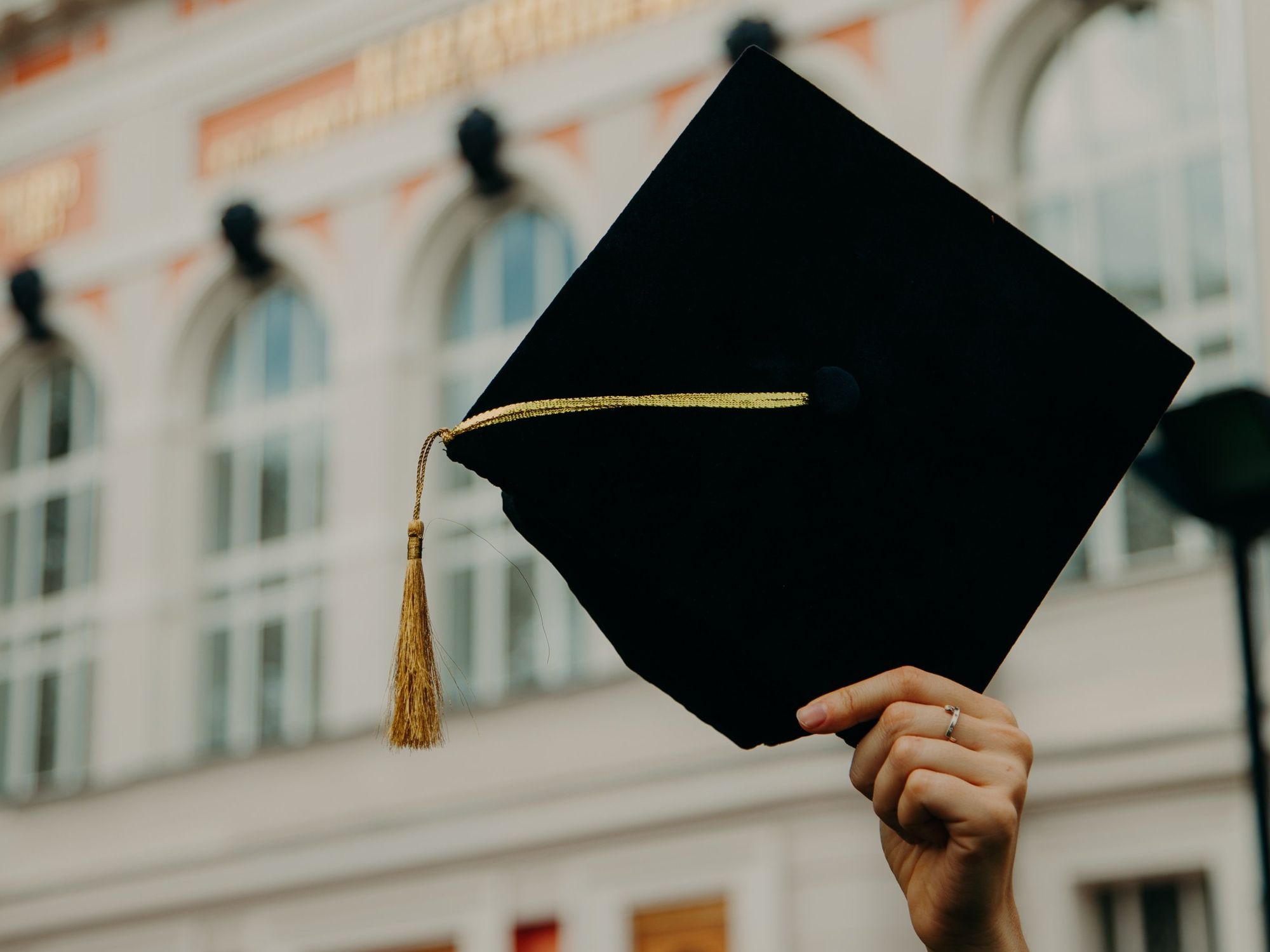 image of ​a person holding a graduate cap