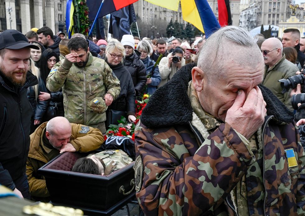 Image of ​People crying and paying their respect around the coffin of the Ukrainian soldier during his funeral ceremony