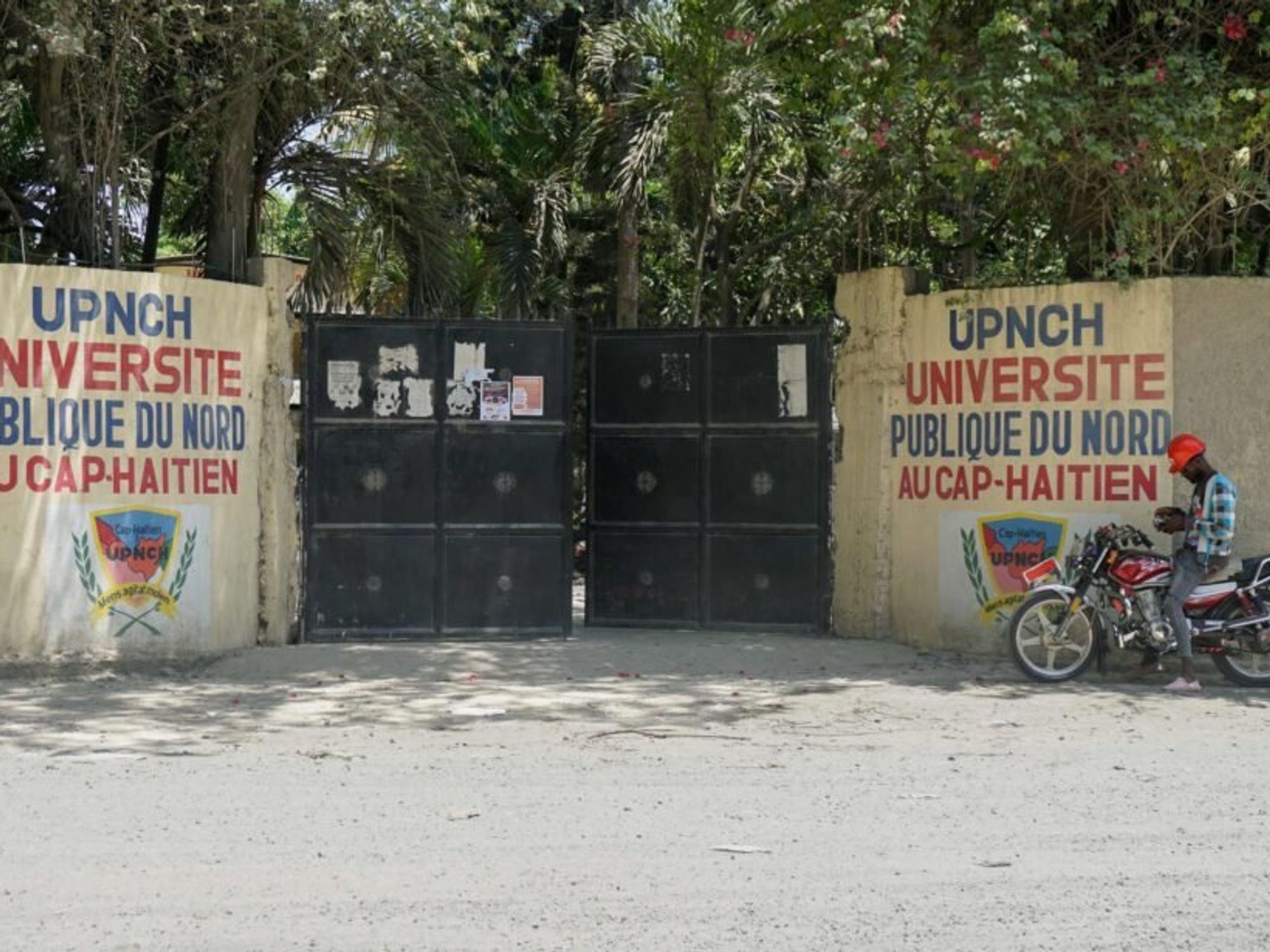 image of gates to a university and a sandy road