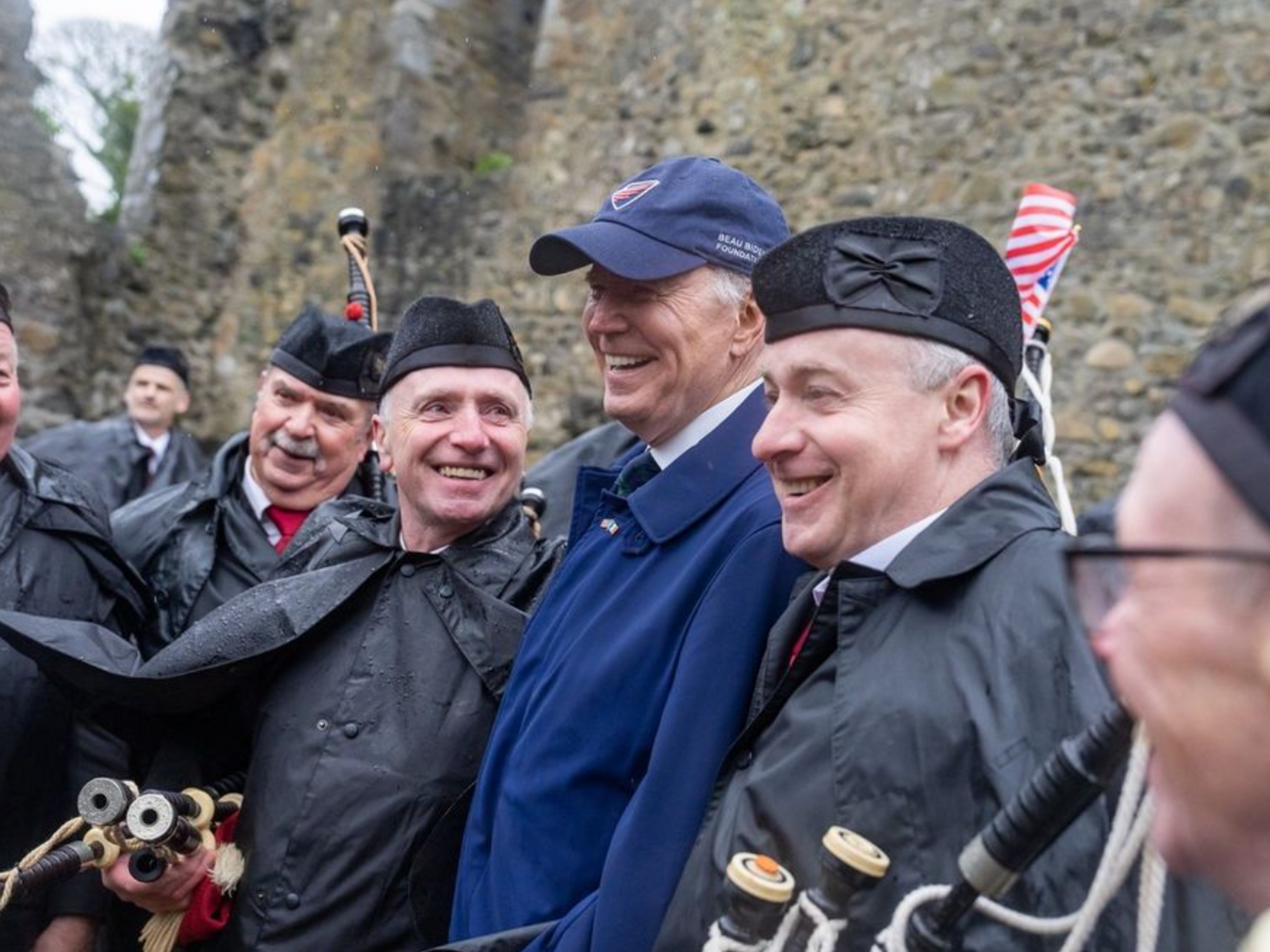 Image of Joe Biden with a Pipe band laughing together.