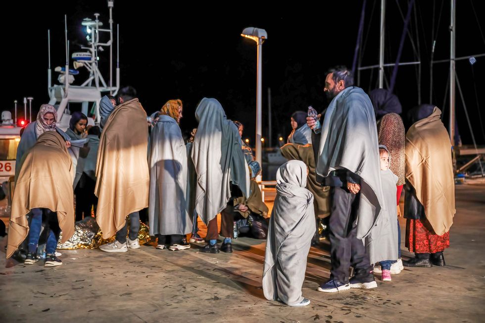 Image of migrants seen covering themselves with blankets on their arrival at the port