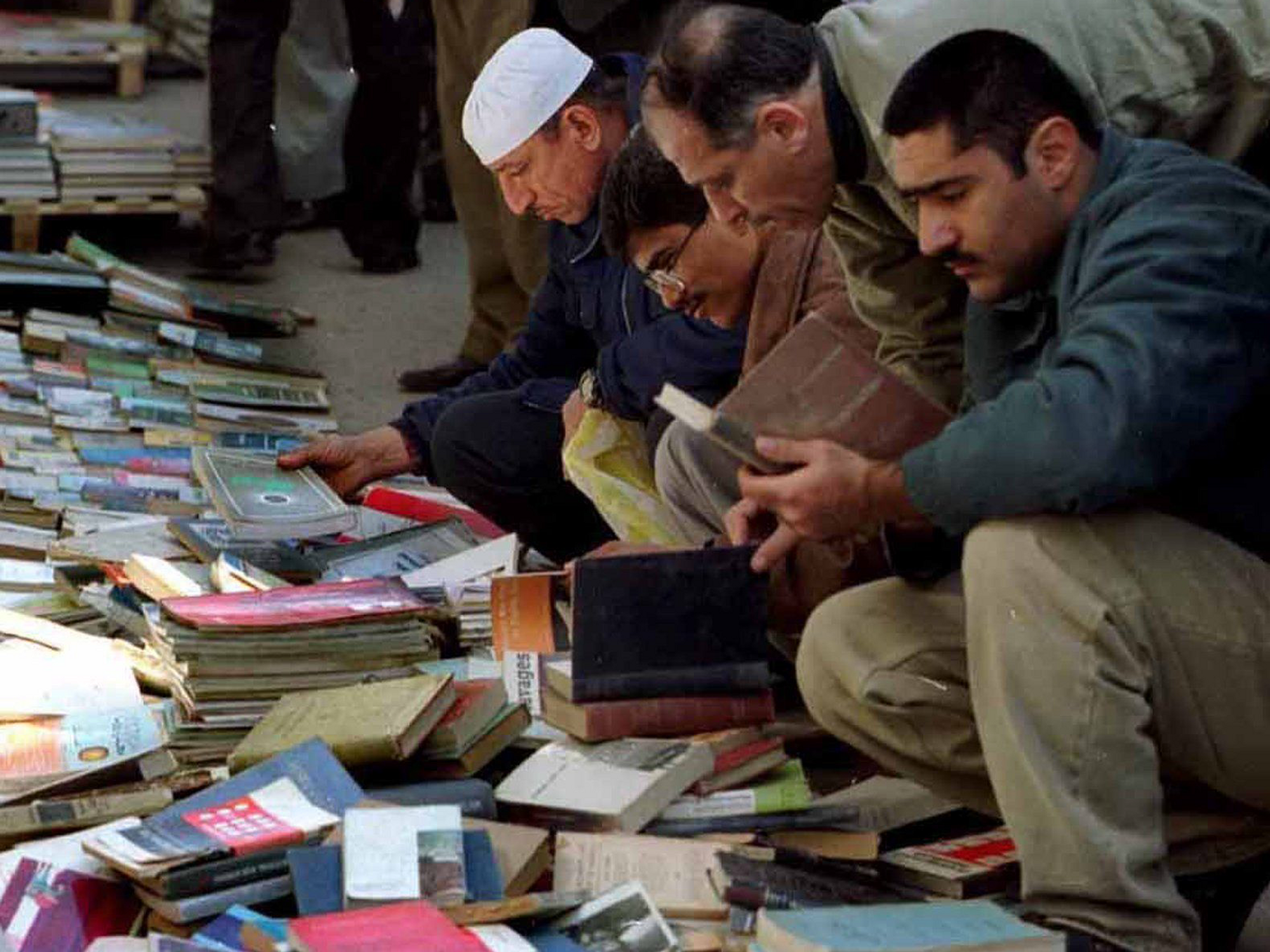 Image of people looking through books in a book market in the street.