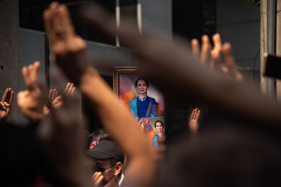 Image of protesters holding portraits of Aung San Suu Kyi and make three finger during a demonstration in Bangkok, Thailand.