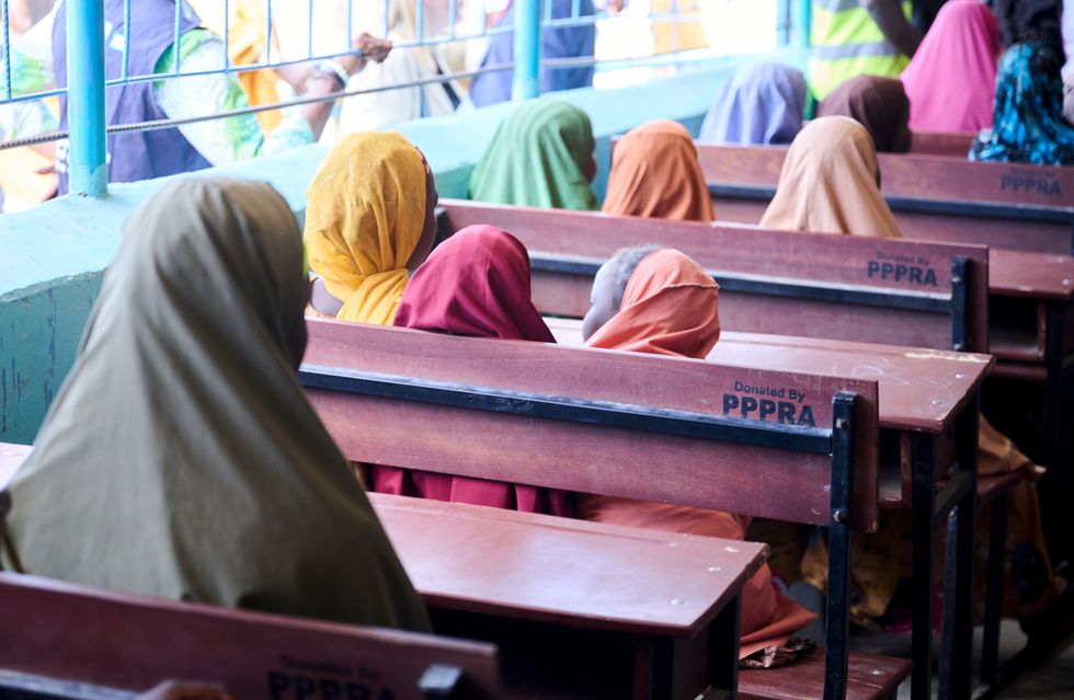 Image of schoolgirls sitting on benches in a classroom.