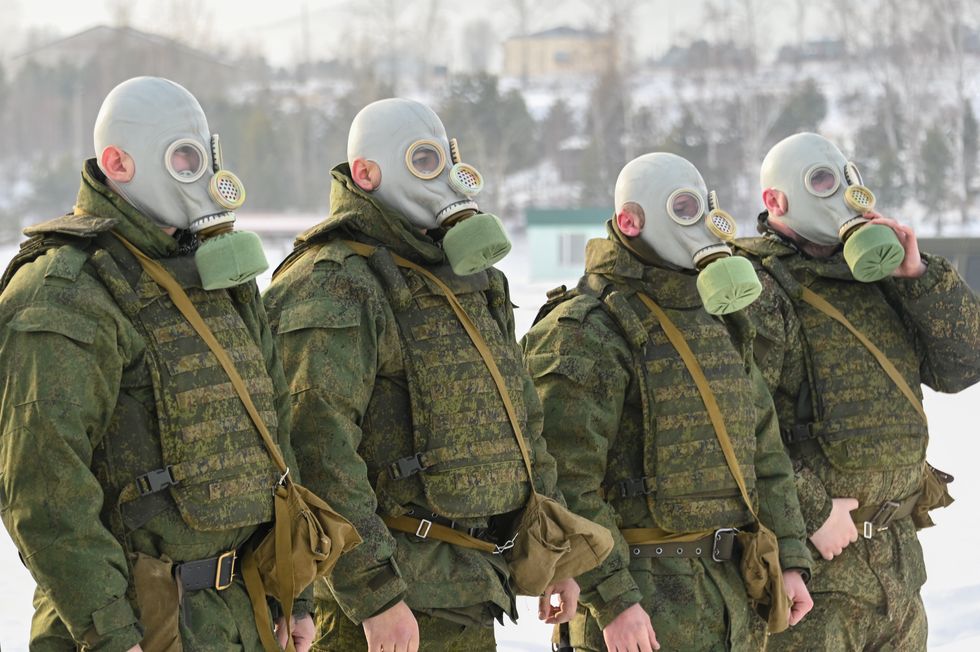 Image of servicemen mobilized as part of partial military mobilization wear gas masks as they take part in a military exercise at a shooting range of the Russian Eastern Military District.