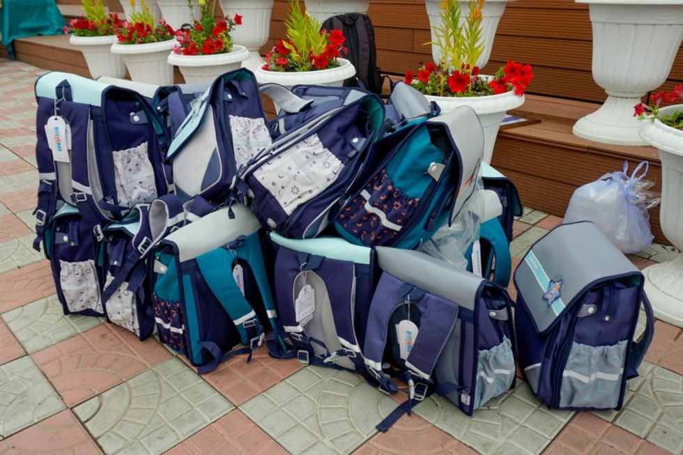 Image of several blue backpacks stacked on top of each other on the ground, ready to be gifted.