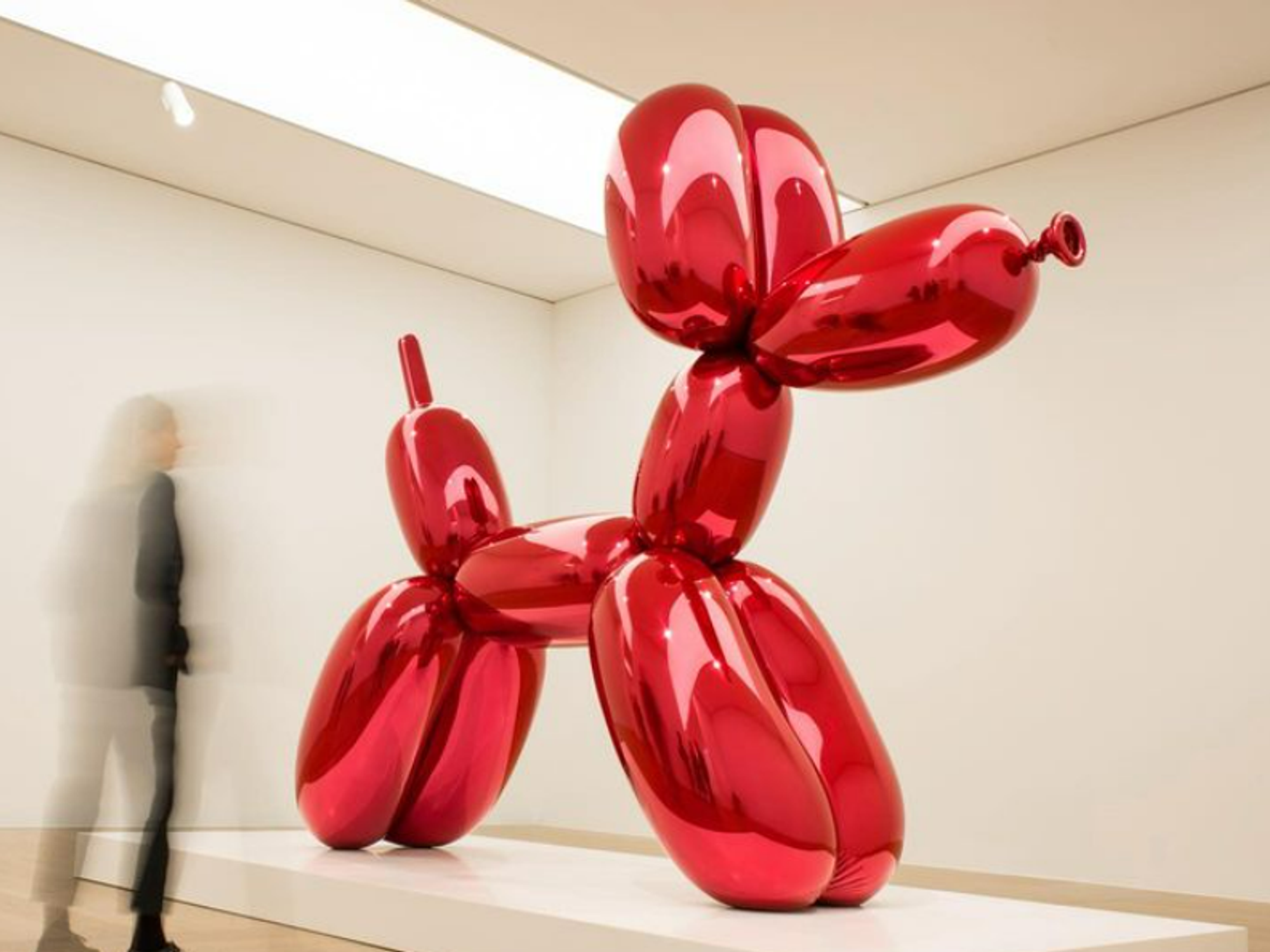 Image of the art piece called Balloon Dog (a giant red dog made of balloon) in a museum.