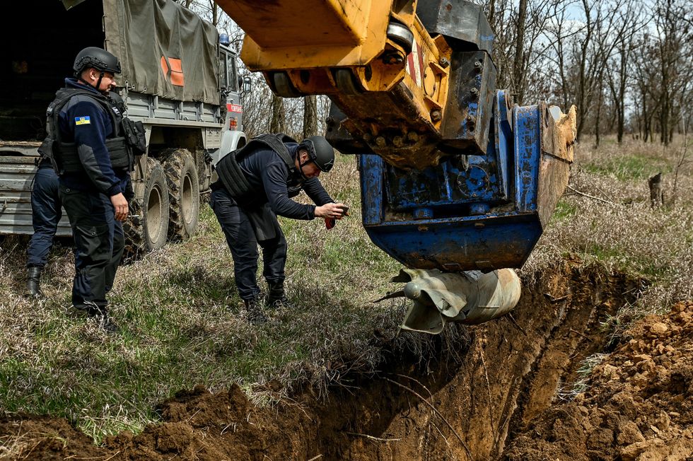 Image of three men removing a bomb from the ground.