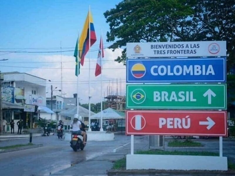 Image of three road signs indicating different countries (Colombia, Brasil, Peru) outside in a street.