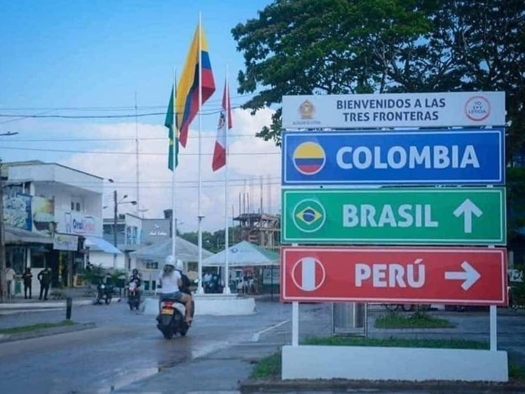 Image of three road signs indicating different countries (Colombia, Brasil, Peru) outside in a street.