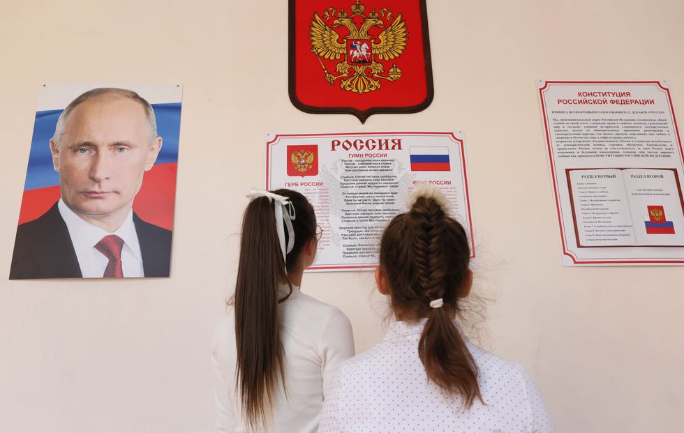 image of two girls reading the Russian national anthem posted on a wall