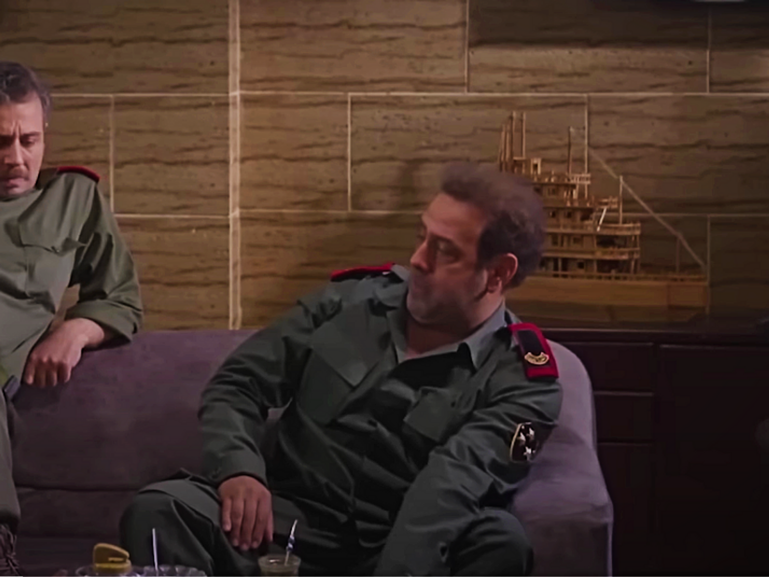 Image of two officers sitting next to and talking to one another on the couch in an office .