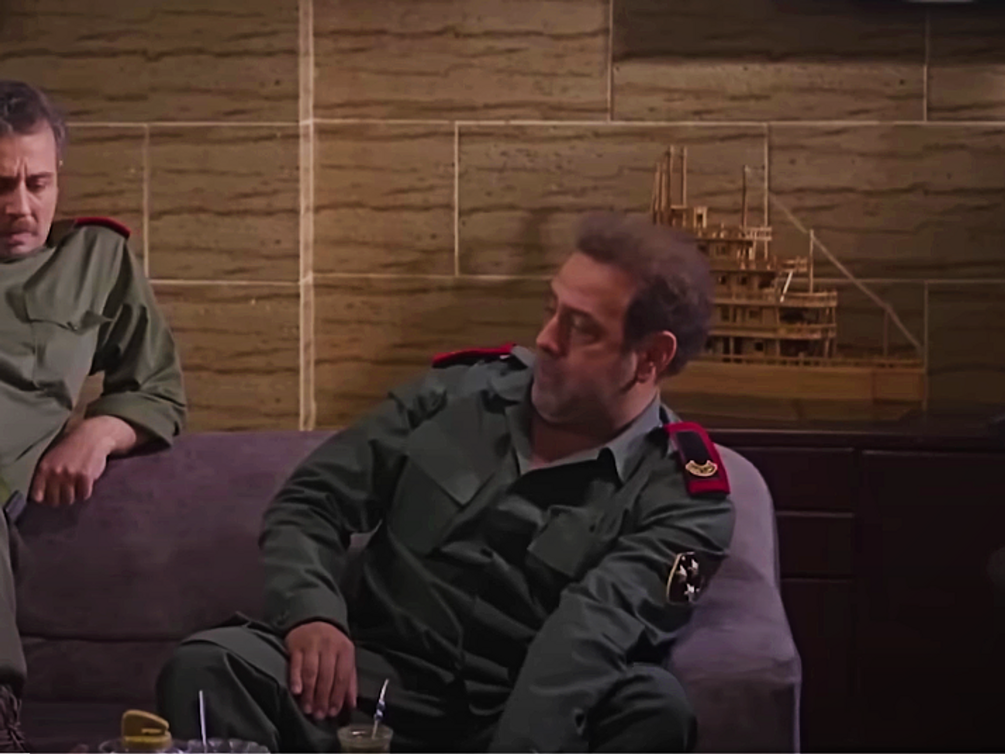 Image of two officers sitting next to and talking to one another on the couch in an office .