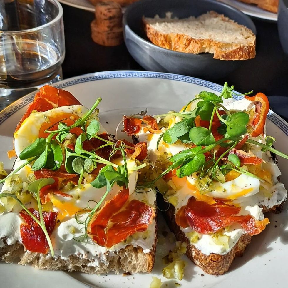 Image of two slices of bread with ham, salad and eggs on it.