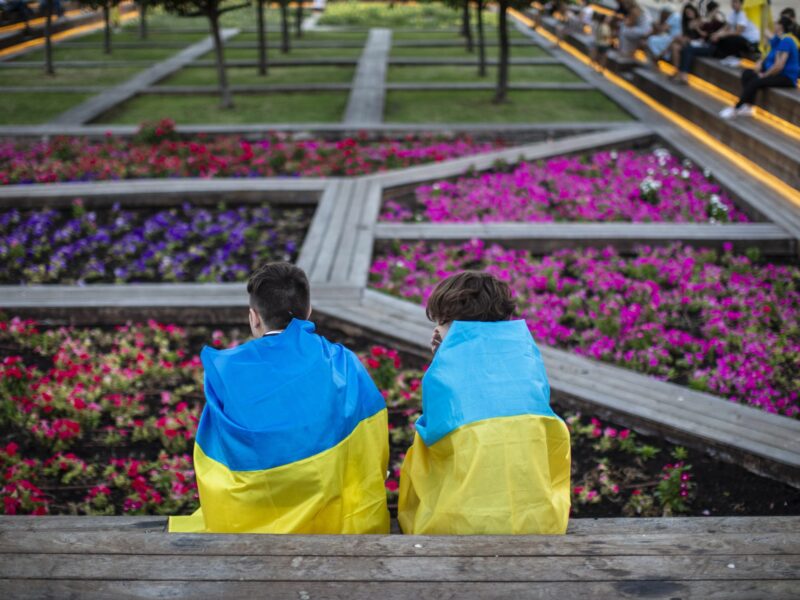 image of Ukrainian children wrapped in Ukrainian flags by some flowers