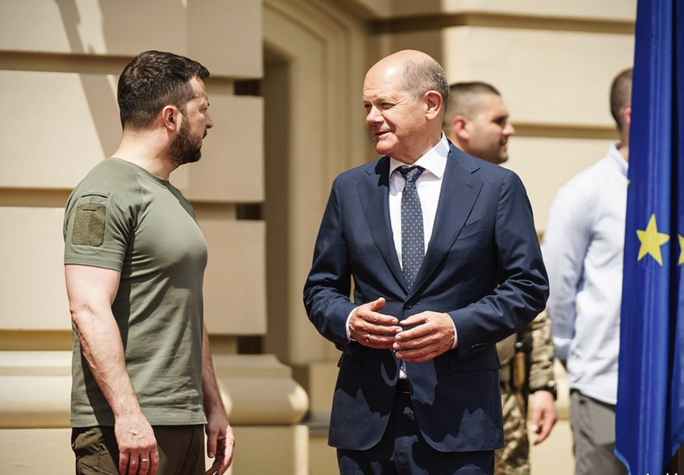 Image of Ukrainian President Volodymyr Zelensky in a kaki t-shirt standing beside German Chancellor Olaf Scholz who's wearing a navy suit.
