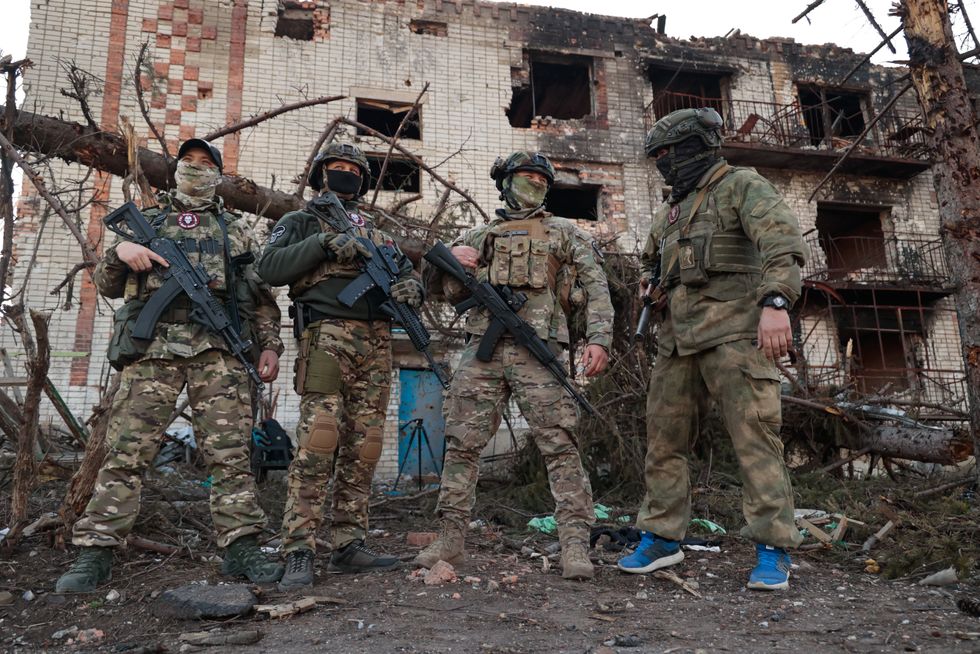 Image of Wagner Group soldiers seen by a damaged building in the city of Artyomovsk (Bakhmut).