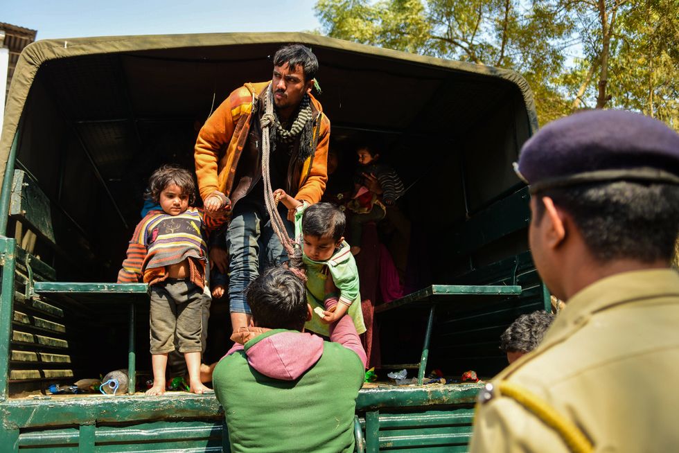 Image showing a man letting children down from a truck. He is one of the 31 Rohingya who were stranded on the India-Bangladesh border for three days are held at the Amtali Police Station.