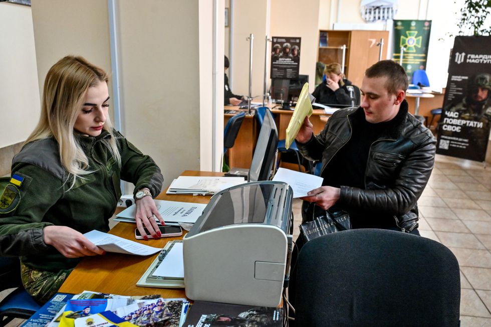 image showing a man who fills in the papers at one of the Administrative Service Centres as he wishes to join the Offensive Guard, Zaporizhzhia, southeastern Ukraine.