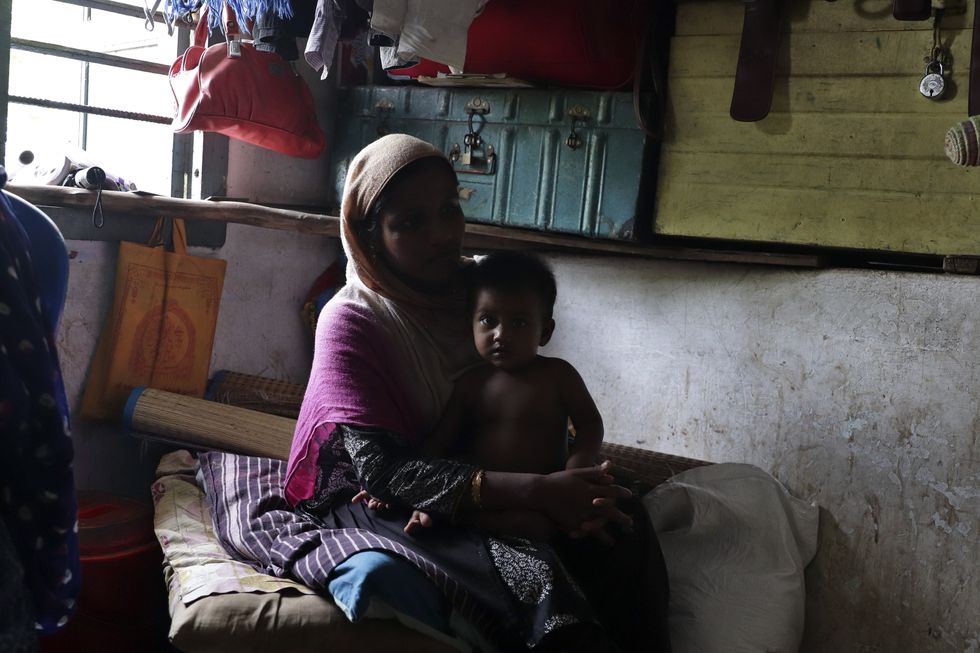 Image showing a Rohingya woman with a child inside a makeshift room.