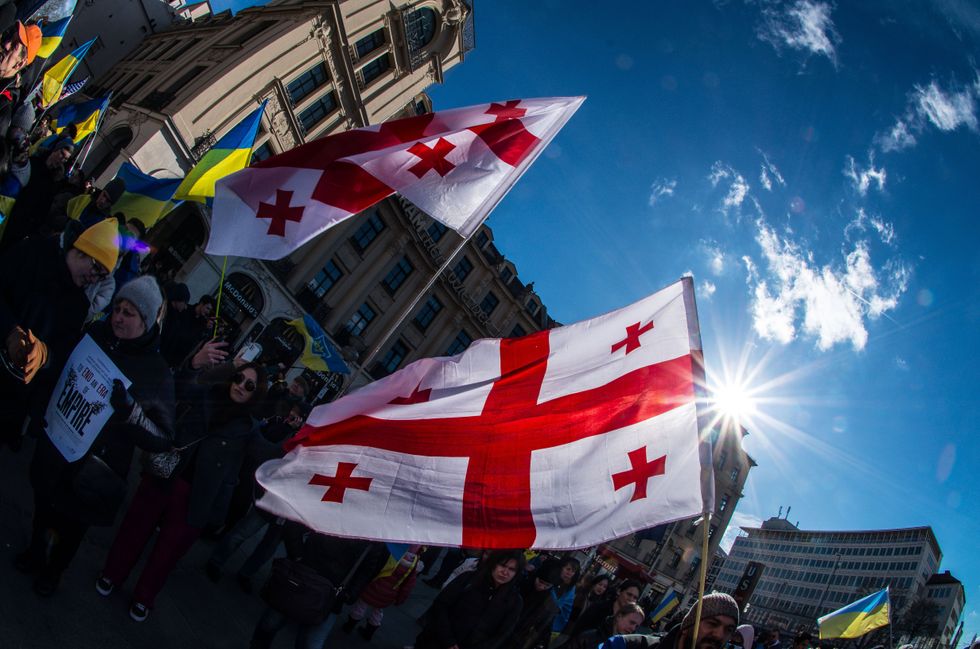 image showing protestors in Munich making demands for peace and the immediate withdrawal of Russia from Ukrainian territory. One protestor holds up the Georgian flag.