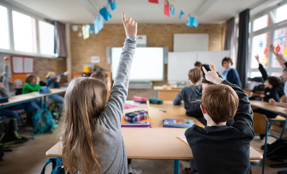 Image showing students of a fifth grade of a grammar school report in class. A Smartboard hangs in front of the classroom.