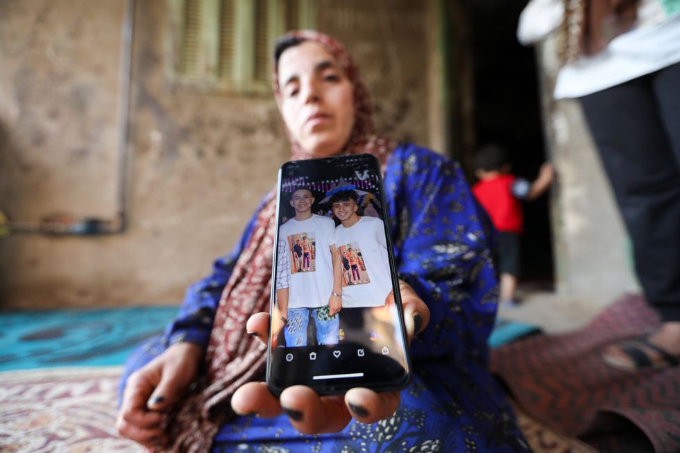 image showing The Mother of Muhammad Ahmed Al-Sayed, who is among the missing after the Greek boat sank on June 14, holds her son's photo in front of their home.