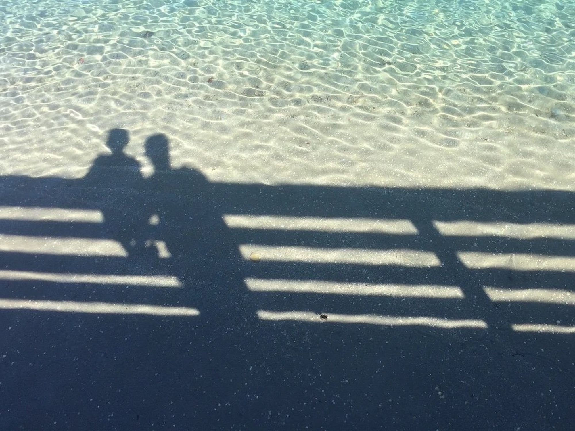 image showing the shadow of a man and boy reflected on ocean